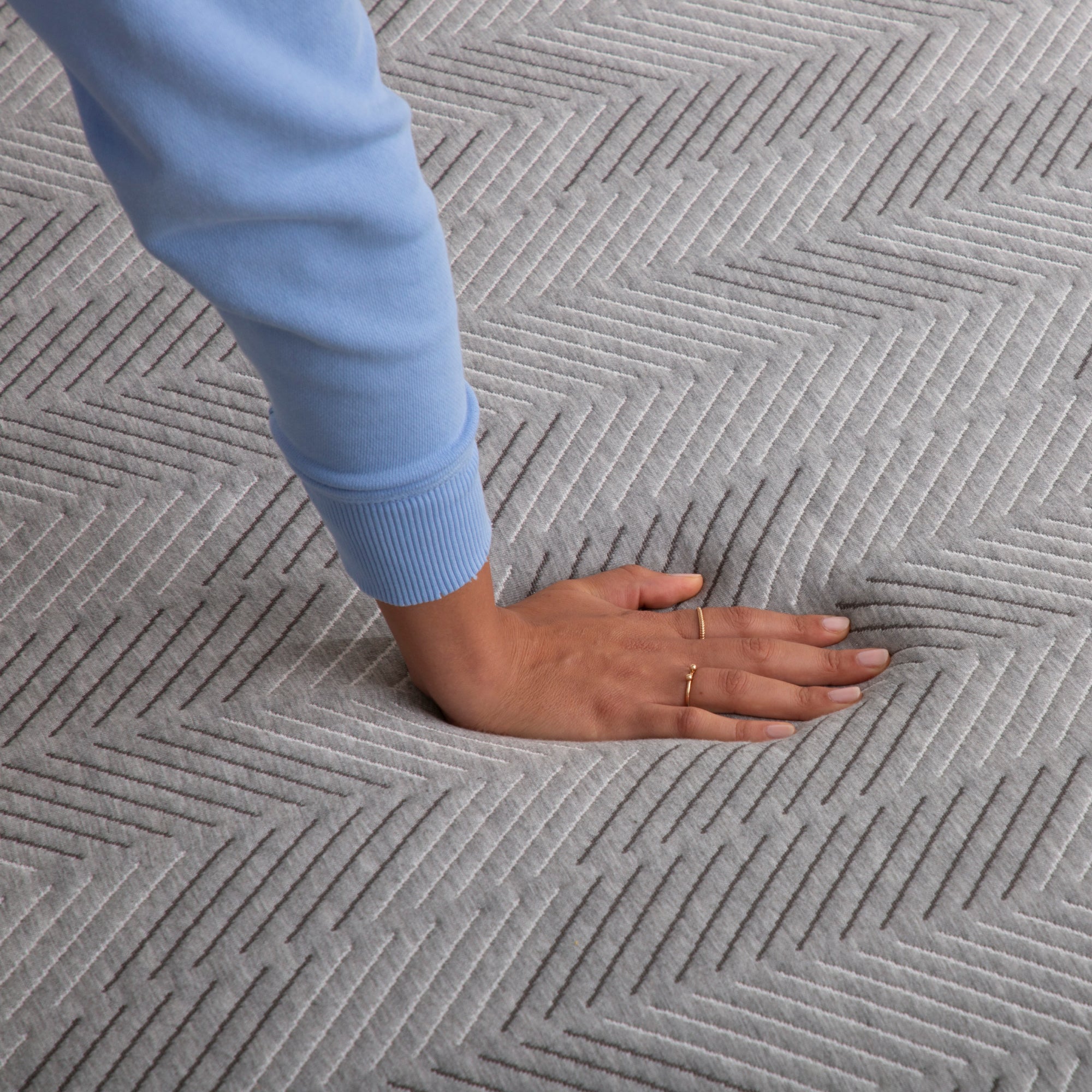 Hand pressing down on Hybrid Firm mattress