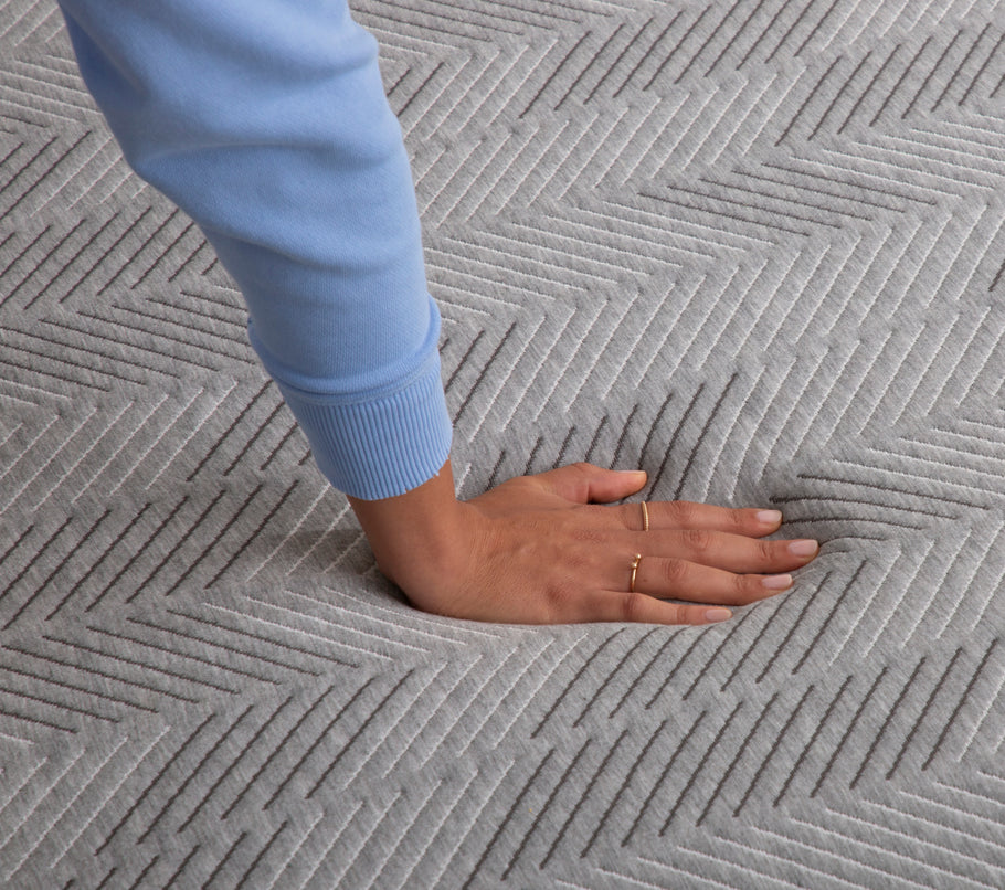 Hand pressing down on Hybrid Firm mattress