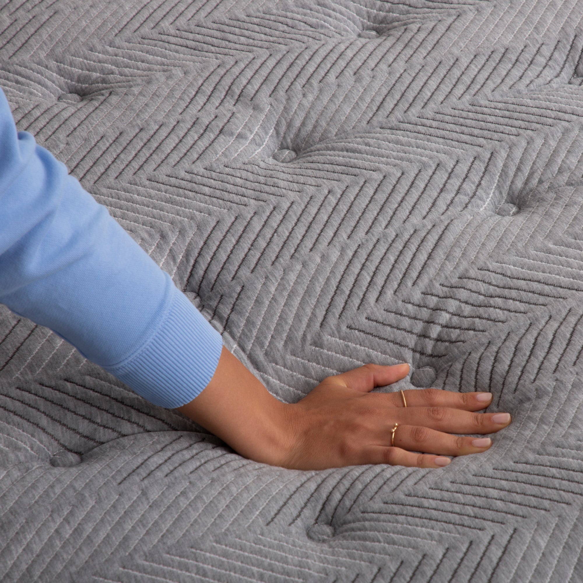 Hand pressing down on quilted plush mattress