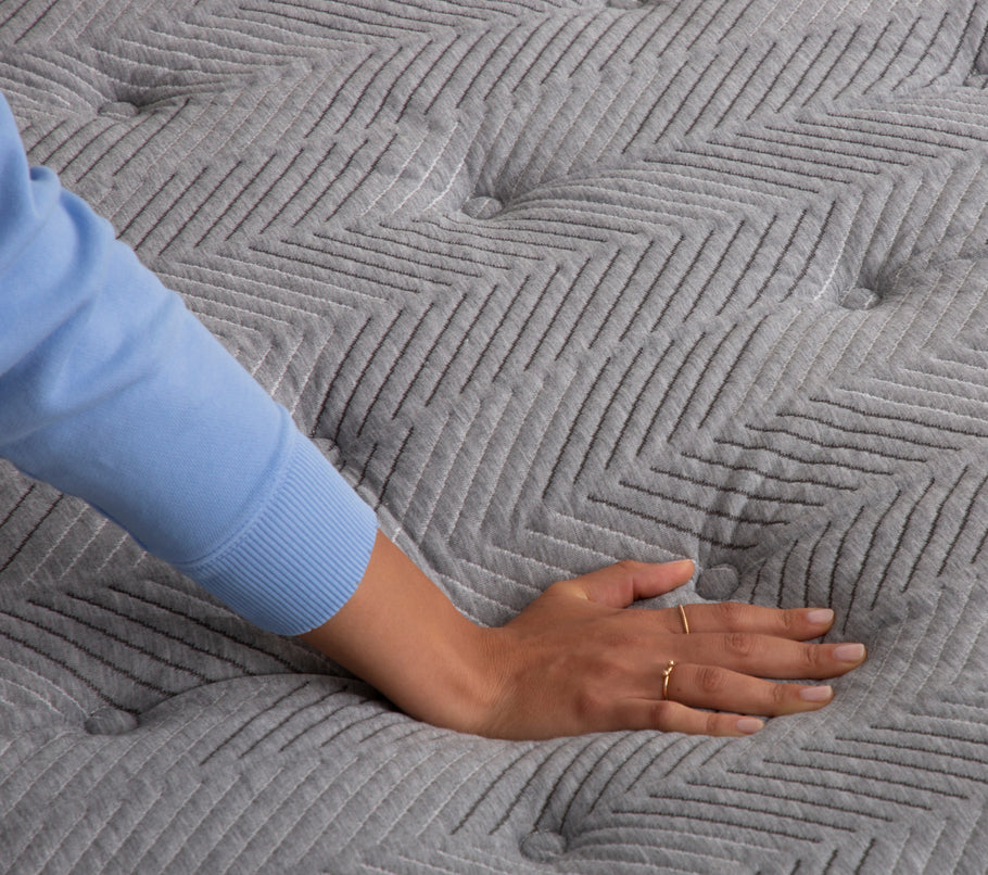 Hand pressing down on quilted plush mattress